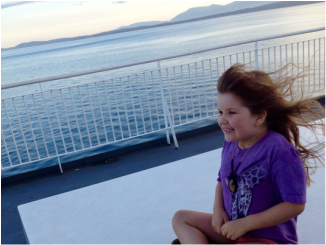 Little girl in the wind on the upper deck on the ferry