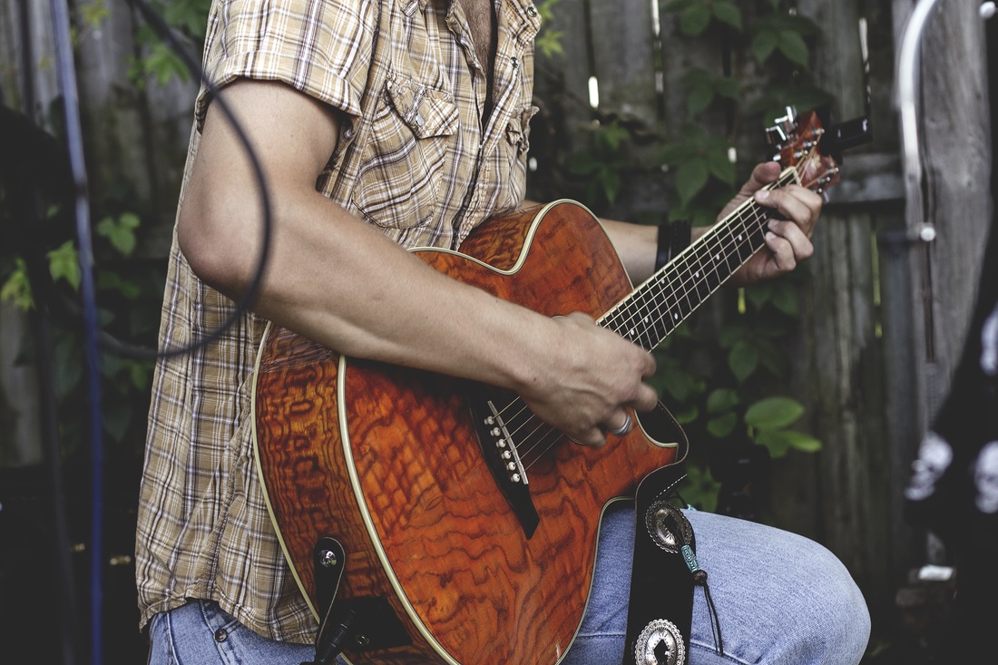 Man in a garden setting playing his guitar