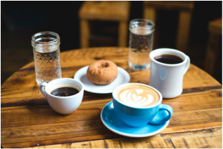 Coffee cups, water glasses and a doughnut on a rustic table