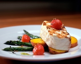 Lovely piece of grilled fish on asparagus, potatoes and tomatoes