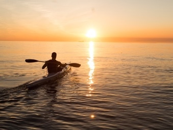 Kayaker paddling into the sunrise